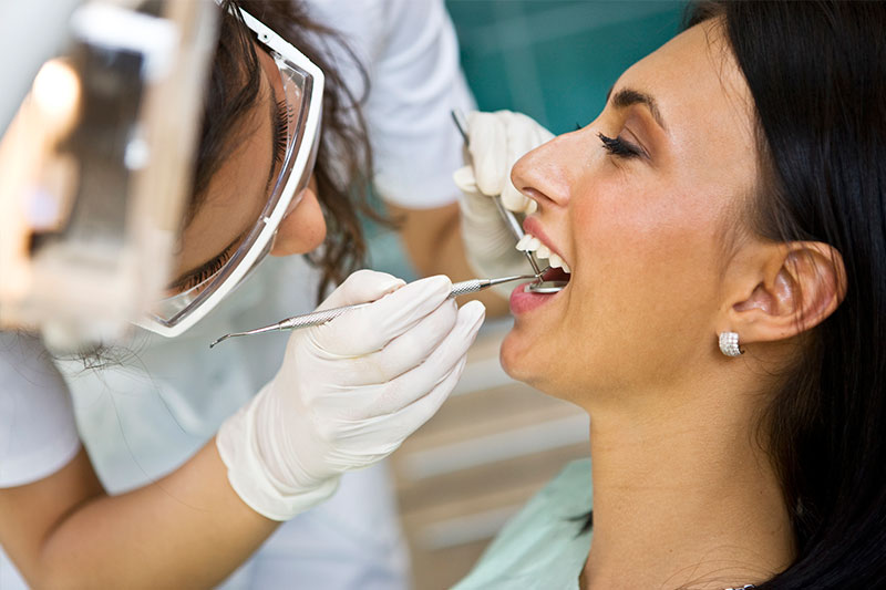 dentist examining patient's mouth in dental exam and cleaning page