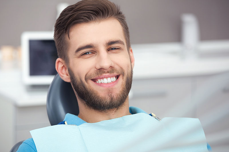 man smiling in dental chair on dental fillings page