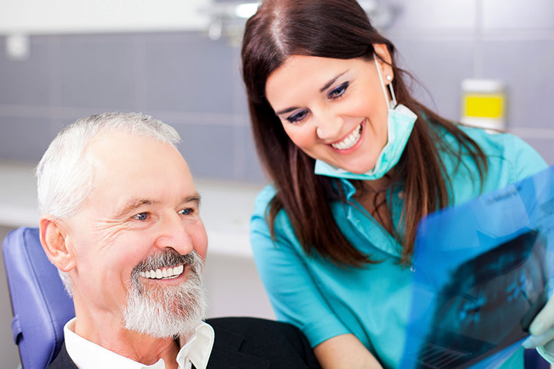 Dentist showing person their x rays on the dental implants page