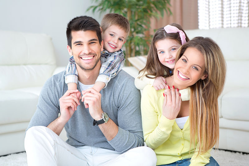 family of four smiling in a living room on new patient page