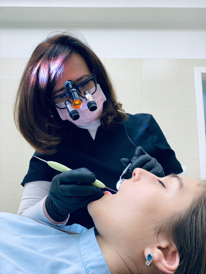 Dentist uses dental instruments to clean patient's teeth